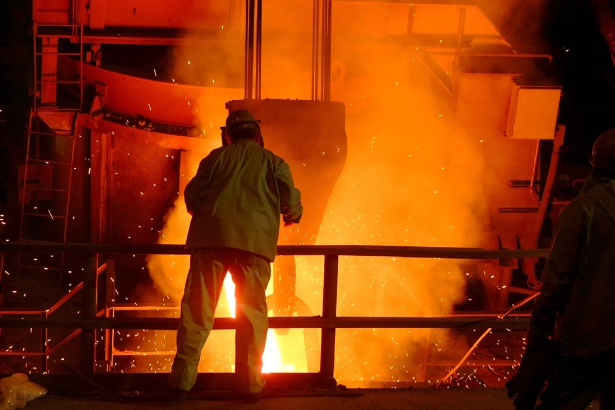Steel mill worker beside molten metal and sparks